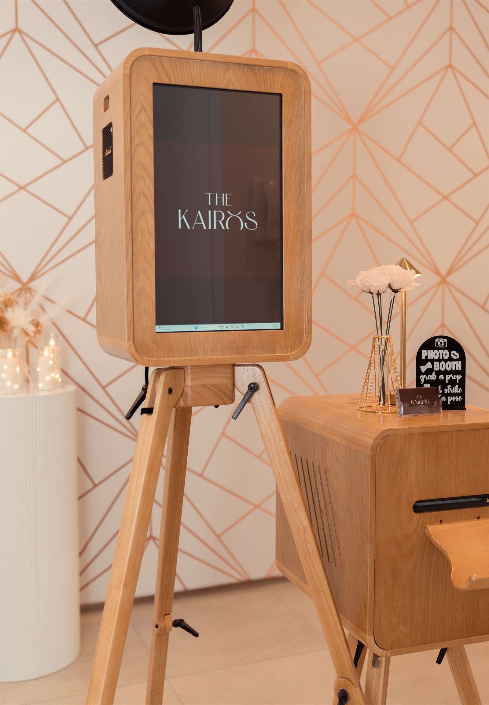 The Heritage photo booth and matching wooden print station with flowers and a gold lamp